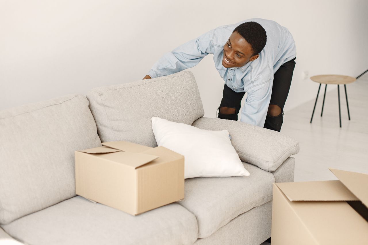about-02 Jeune homme souriant en rangeant des cartons dans un salon moderne.